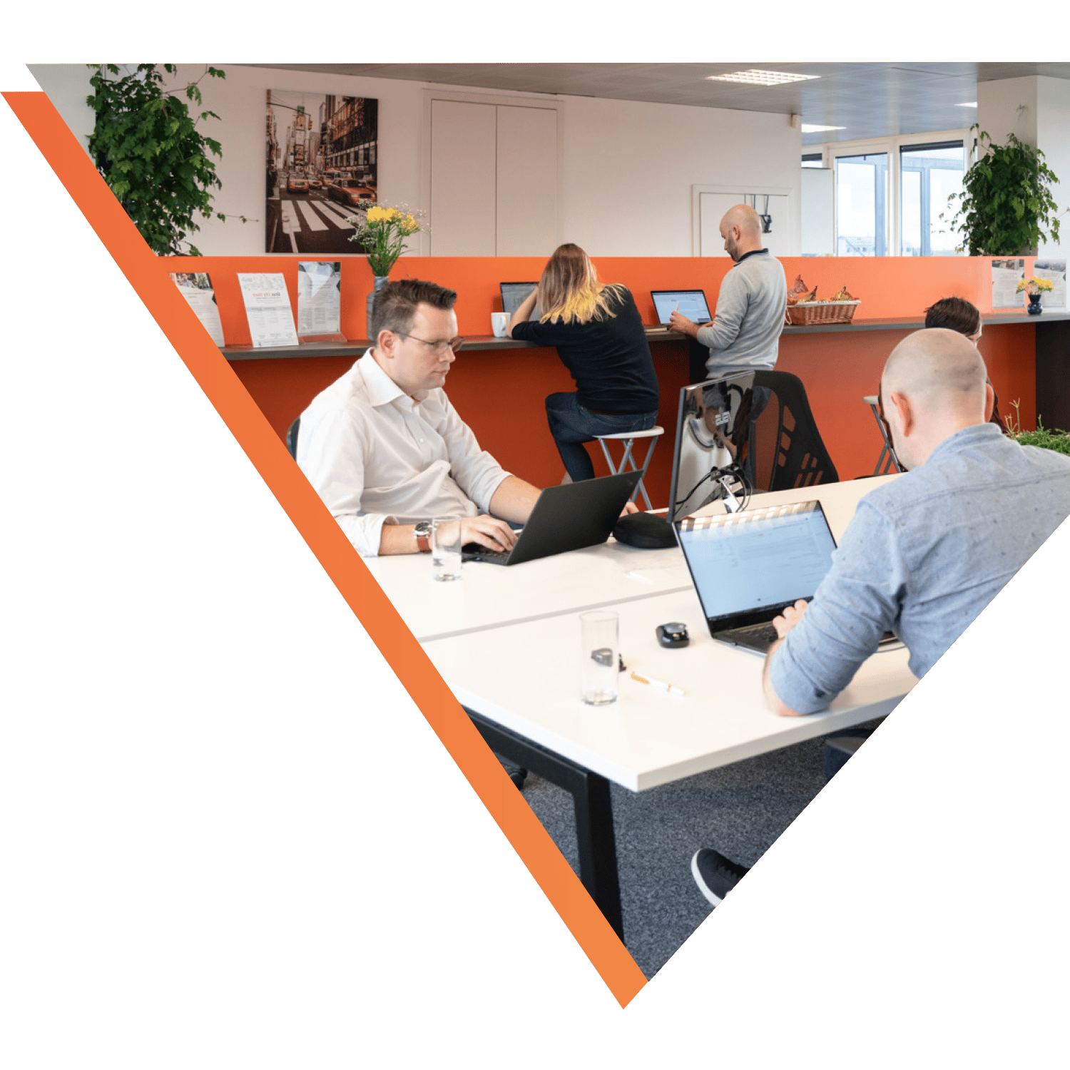 Sirus employees working in a co-working space with an orange accent wall and modern decor.