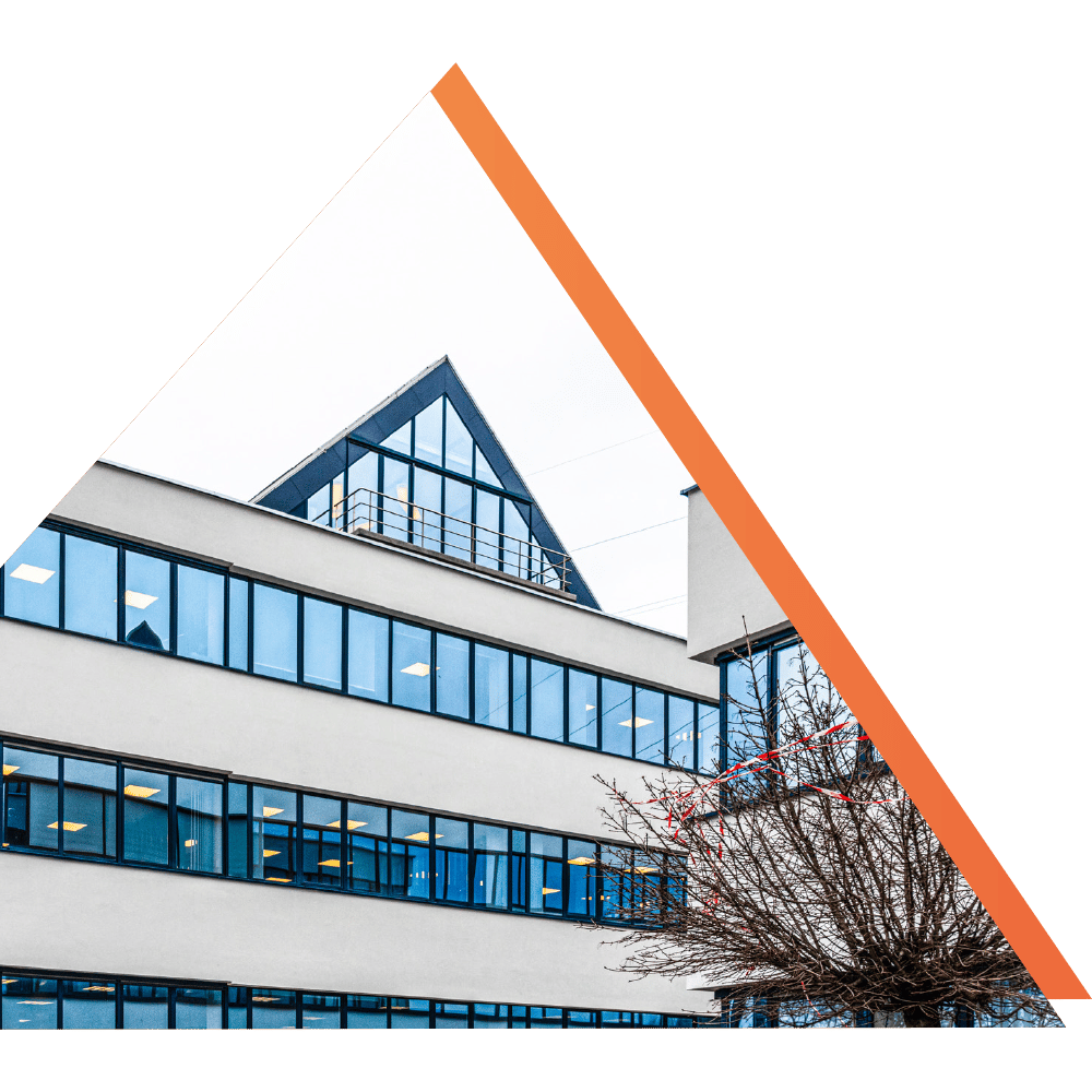 Modern office building with a triangular glass roof and large windows reflecting the sky.