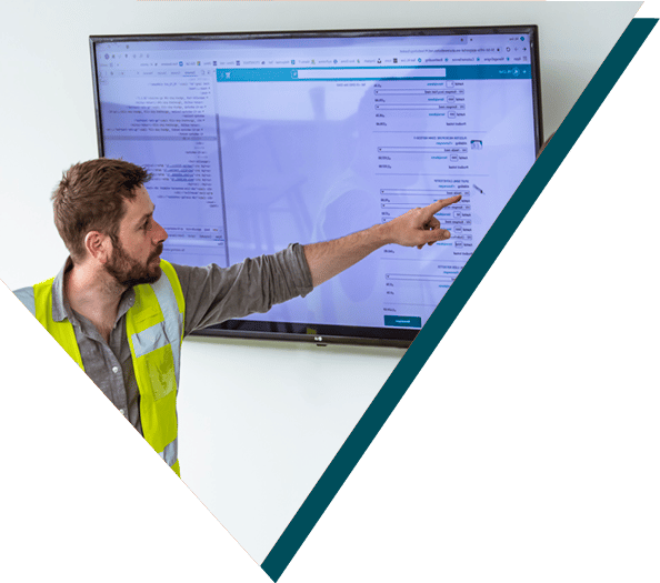 Smart Company Project: Hospital Logistics: A man pointing at a large screen displaying a software interface, conducting a presentation in an office setting.