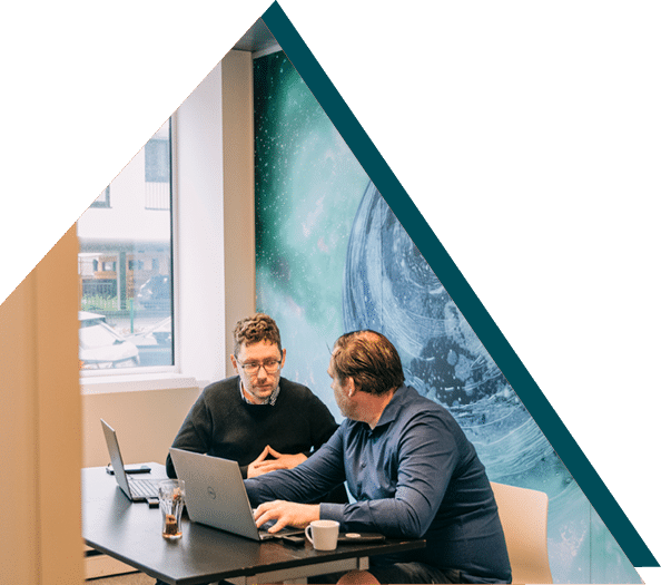 Two Sirus members having a discussion in a meeting room with a galaxy-themed wall at Sirus.