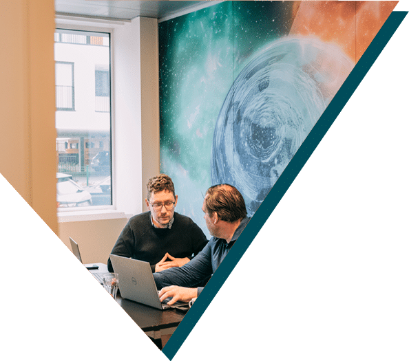 Two Sirus members having a discussion in a meeting room with a galaxy-themed wall at Sirus.