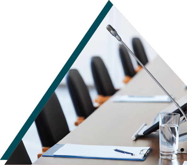 Photo of an empty meeting room with a microphone, glass of water, and notepads on the table, representing municipal council sessions.