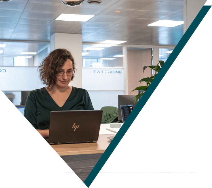 Woman with curly hair and glasses working on laptop in modern office environment at Sirus IT company