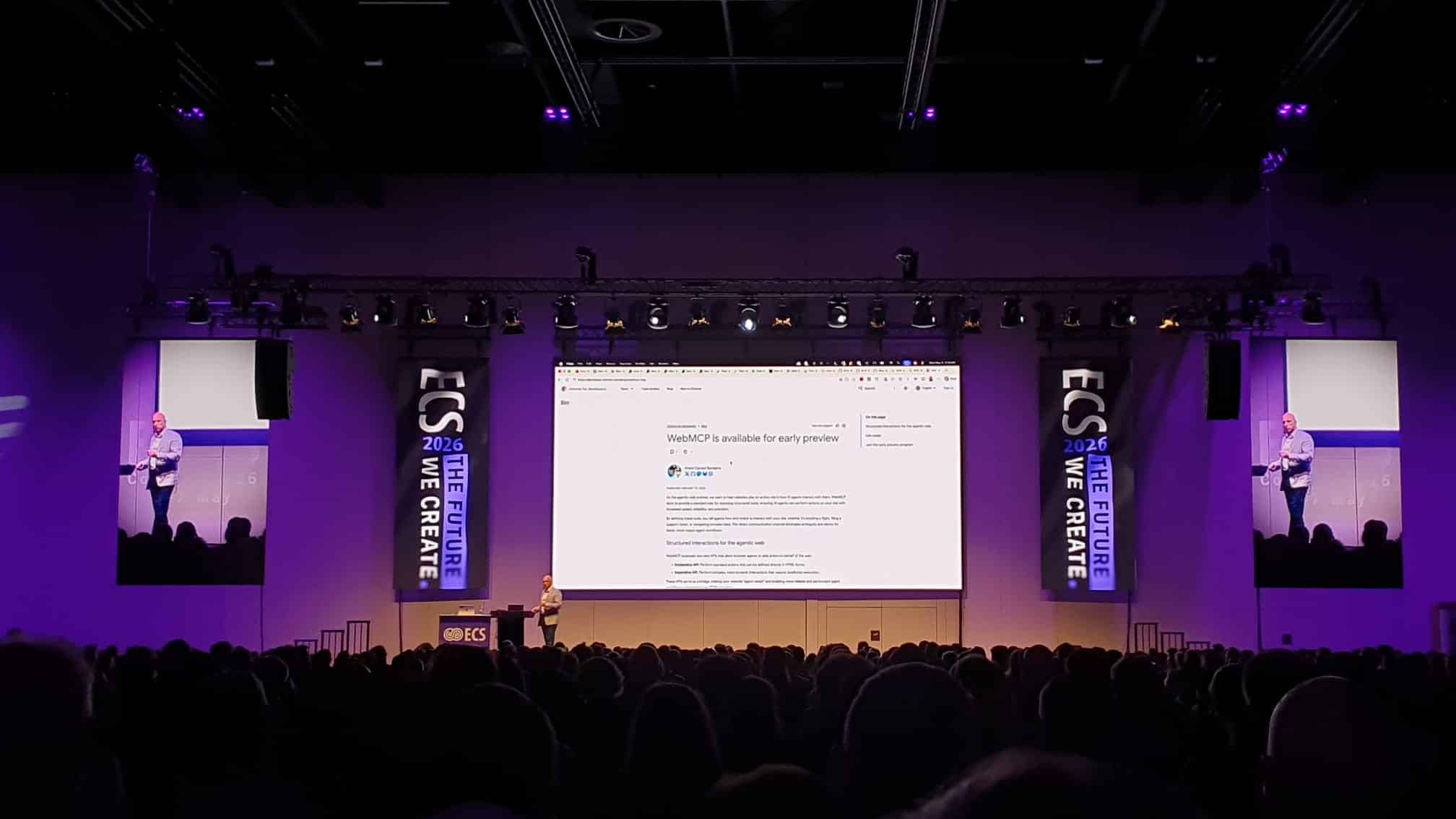 Speaker presenting at ECS European Collaboration Summit conference with large audience and purple stage lighting