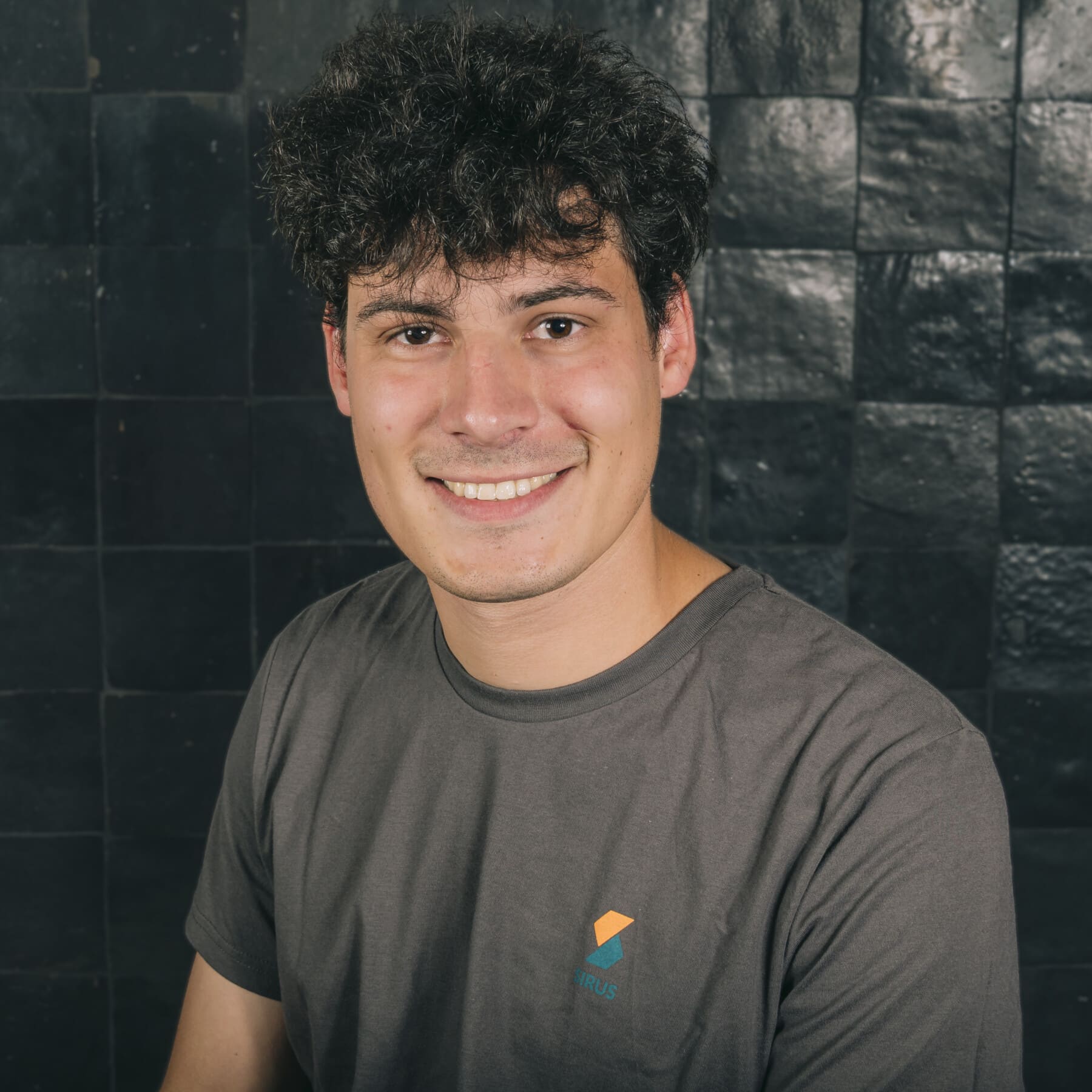 Hannes Dendoncker, Data Engineer at Sirus, smiling against dark brick wall background