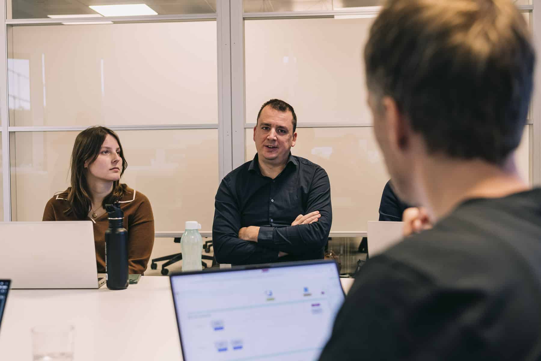Sirus team members collaborating in a meeting room, discussing a software project with laptops open on the table