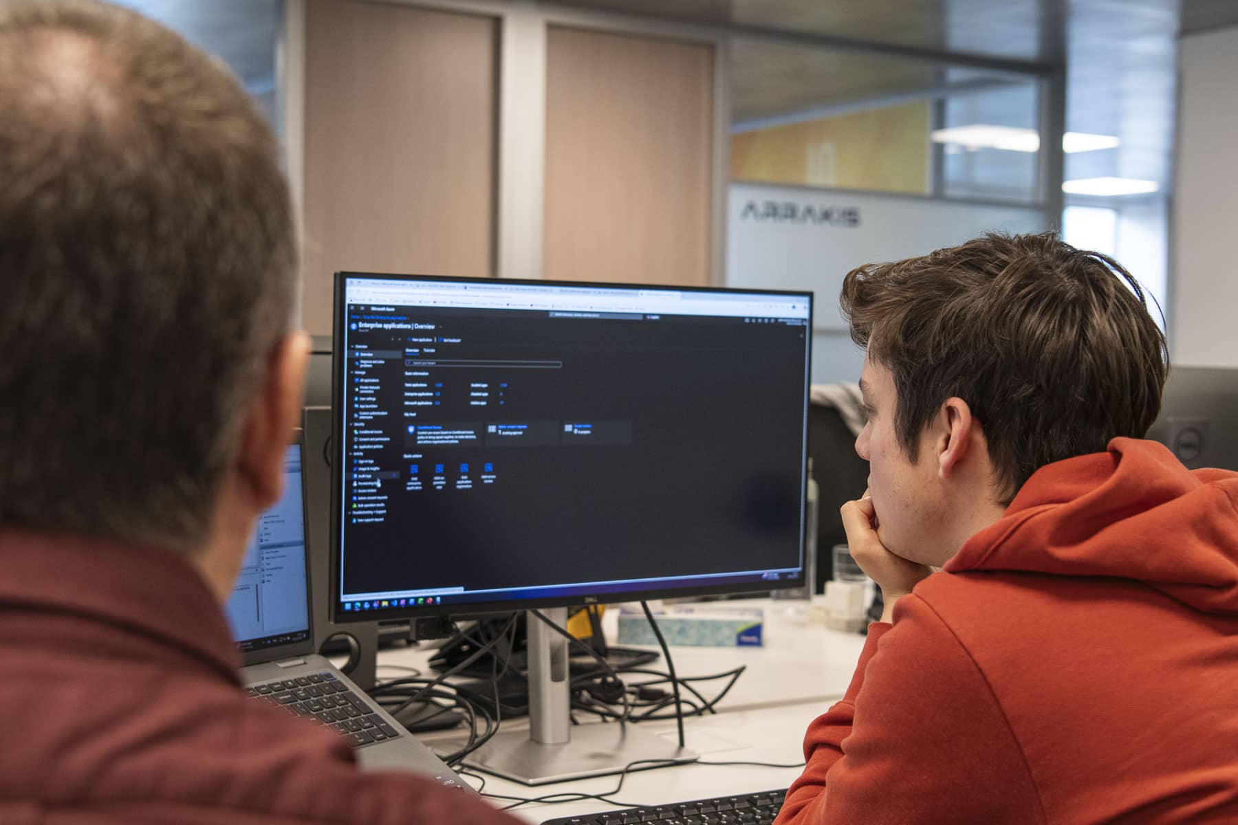 Two Sirus IT consultants collaborating at a desk, reviewing Microsoft Azure Enterprise Applications dashboard on a Dell monit